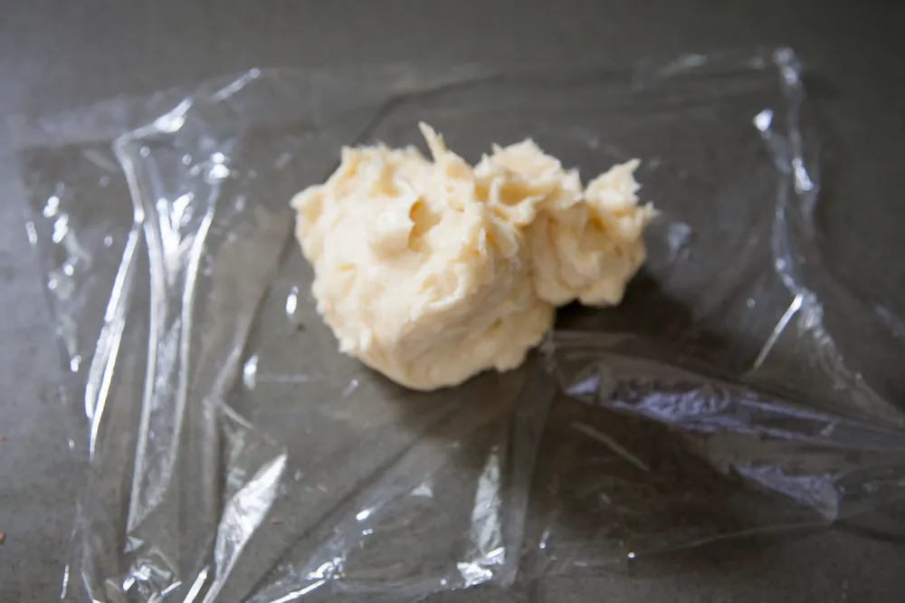 Place the butter in the middle of a sheet of plastic wrap.